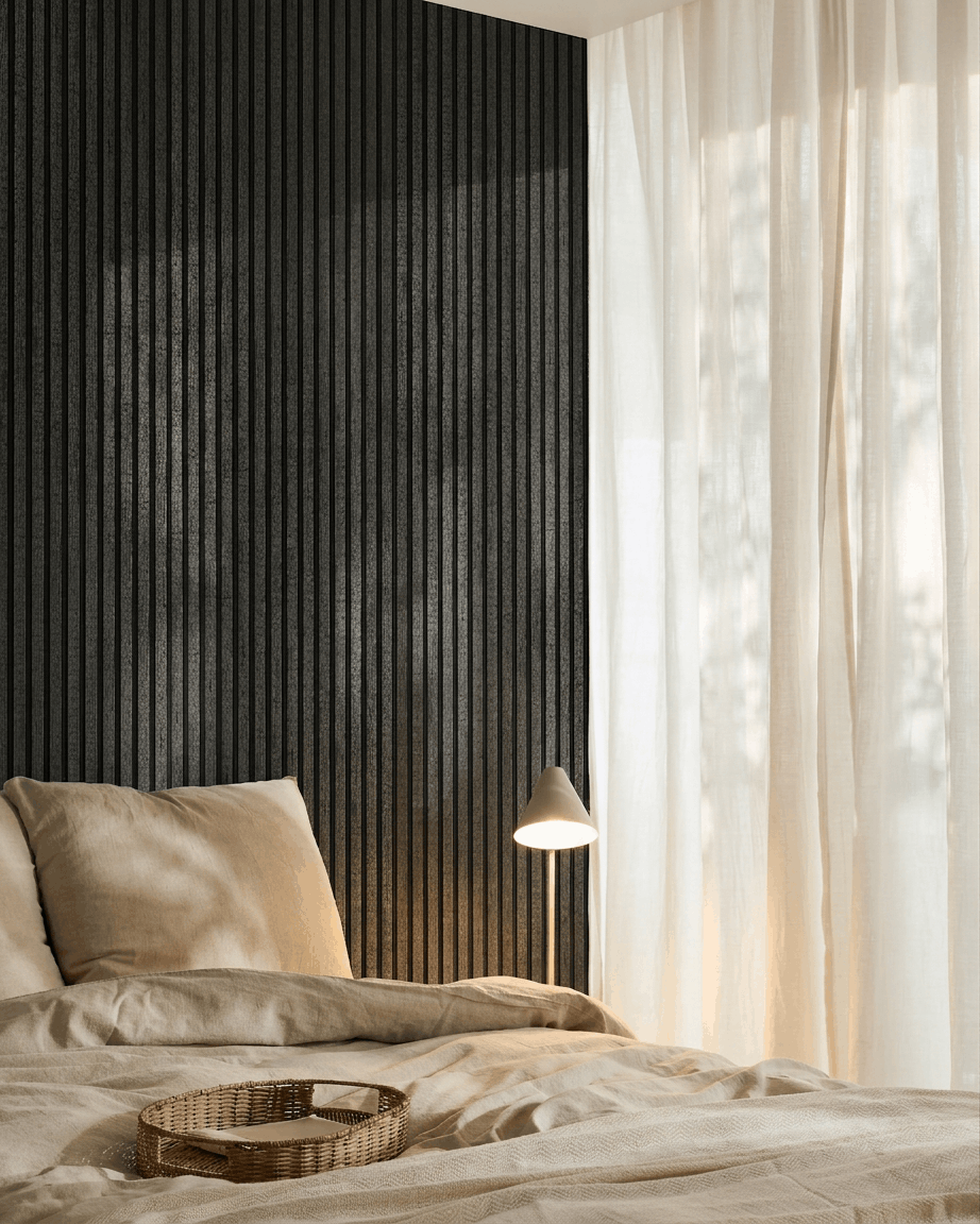 Chambre chaleureuse avec du linge de lit beige, un plateau en rotin, une lampe blanche, des rideaux voilés et un panneau acoustique en bois WoodUpp Akupanel en charcoal fixé au mur.