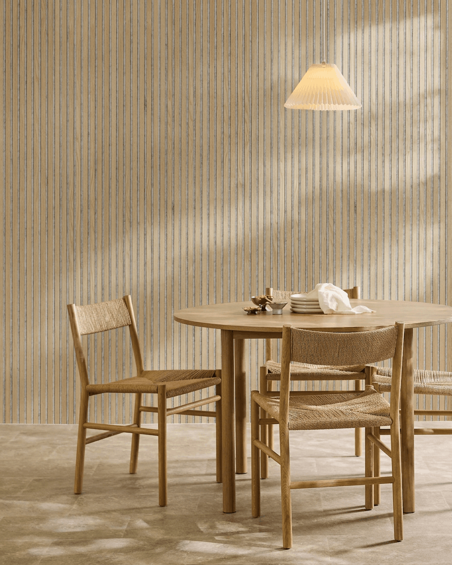 Salle à manger minimaliste avec table ronde en bois, chaises tressées, suspension et panneau acoustique en bois WoodUpp Akupanel en chêne classique avec feutre grey.