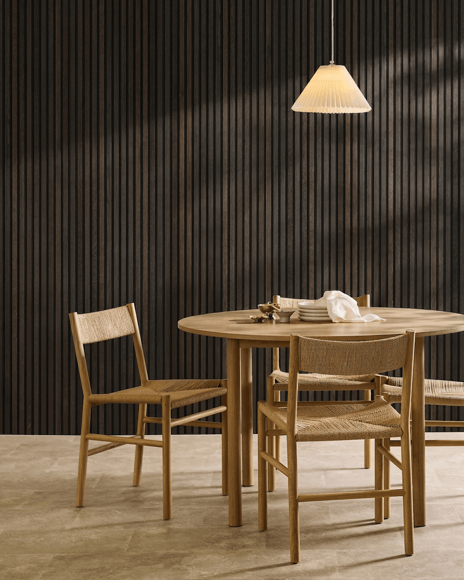 Espace repas minimaliste avec une table en bois, des chaises scandinaves, une suspension et un panneau mural acoustique à lattes WoodUpp Akupanel Rustic Smoked Oak.