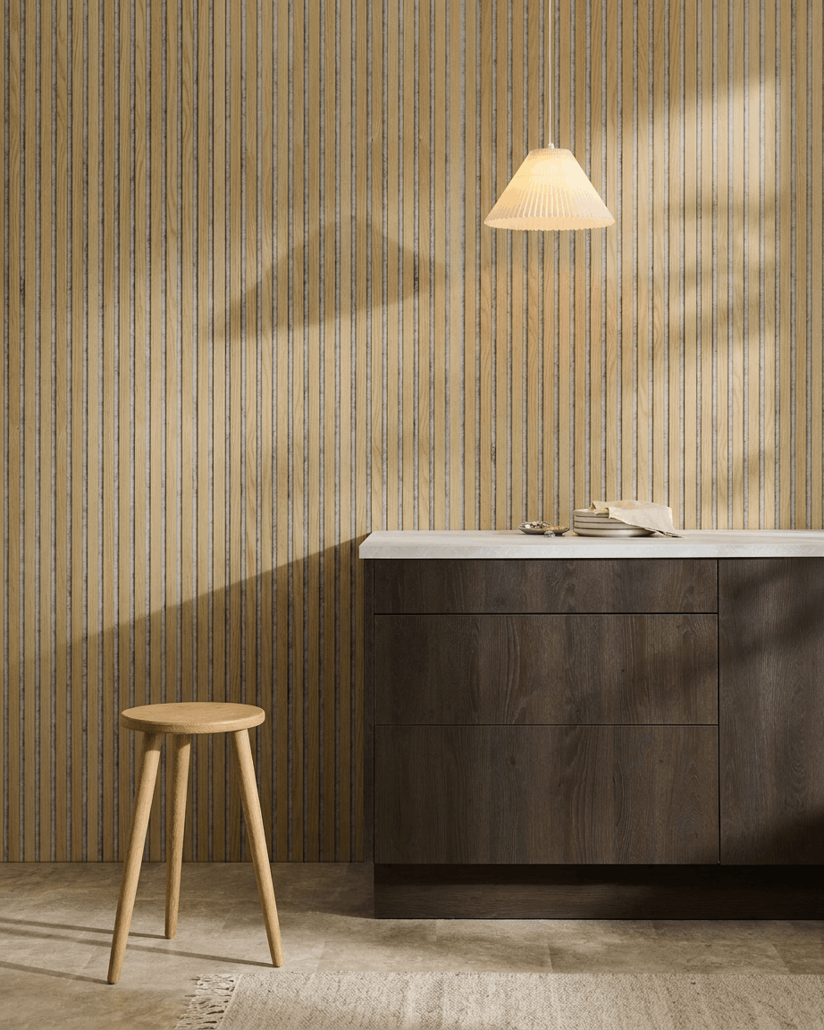 Intérieur nordique minimaliste avec un WoodUpp Akupanel Panneau acoustique en Classic Oak avec feutre Grey, associé à un tabouret en bois, un meuble foncé et un plan de travail blanc.