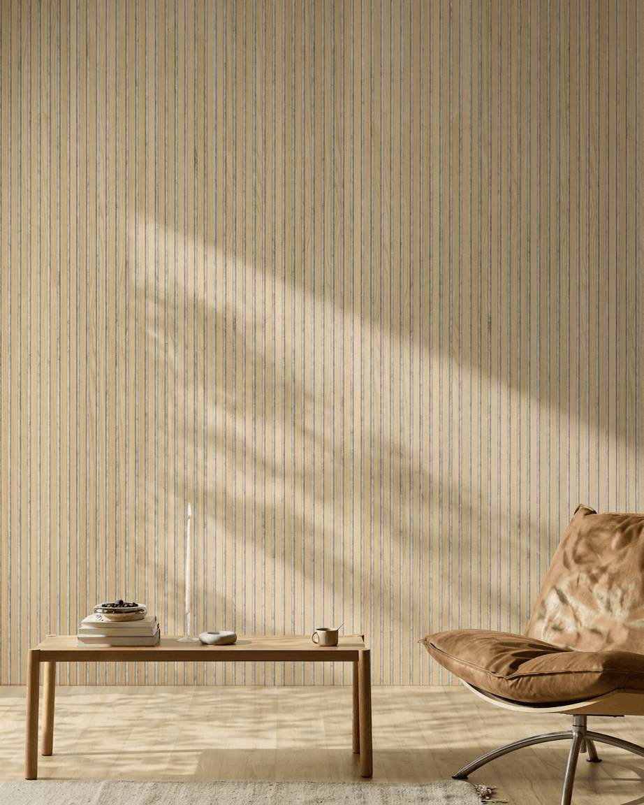 Pièce minimaliste avec un fauteuil en cuir fauve, une table en bois et une bougie. Le panneau acoustique à lattes WoodUpp Akupanel Classic Oak apporte un style nordique et un meilleur confort acoustique.