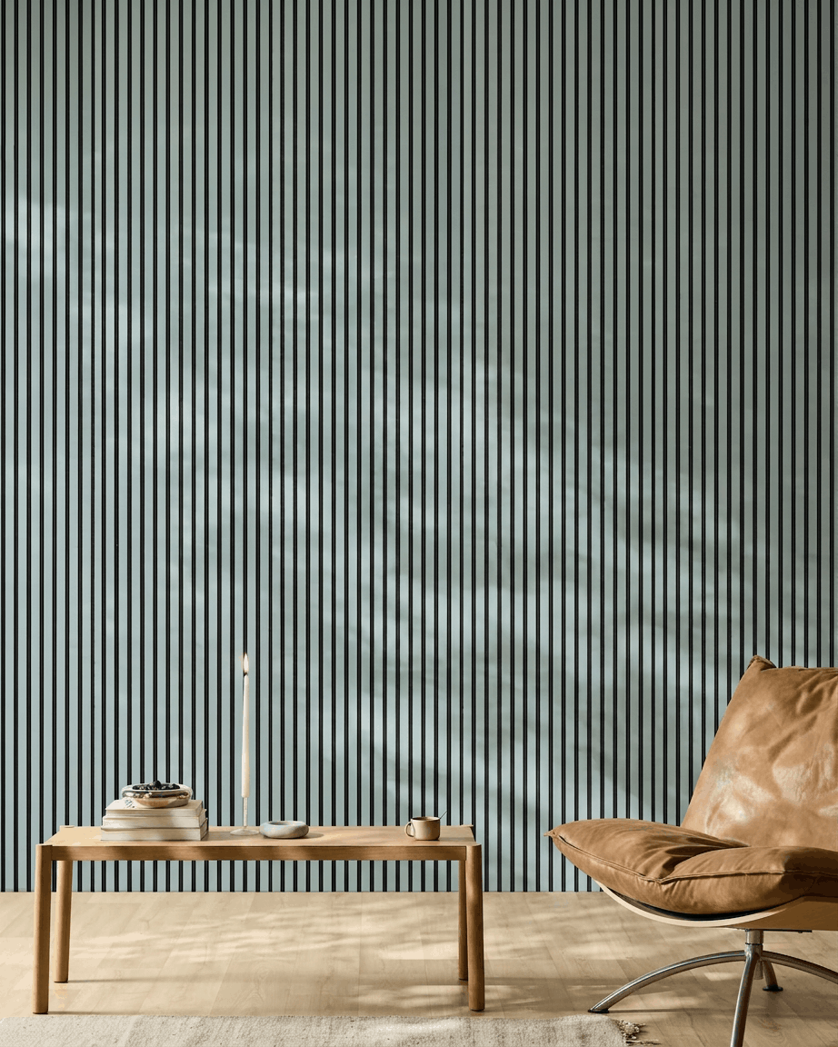 Pièce minimaliste avec un banc en bois, des livres et un fauteuil en cuir brown devant un WoodUpp Akupanel Panneau acoustique en coloris Cloud avec feutre black.