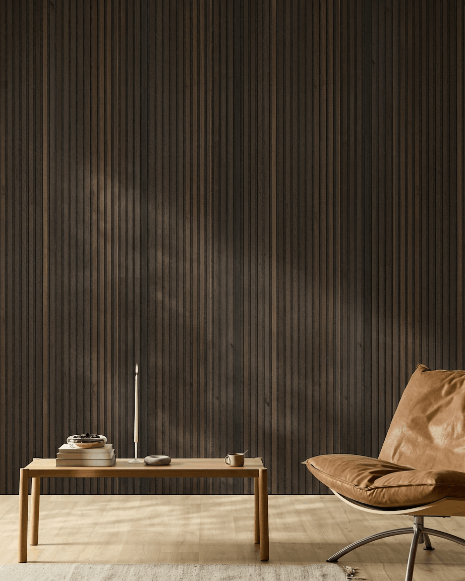 Minimalistischer nordischer Raum mit cognacfarbenem Ledersessel, Holztisch, Kerze und Tasse vor einer WoodUpp Akupanel Natural Wood Rustic Smoked Oak Akustikpaneel Wand.