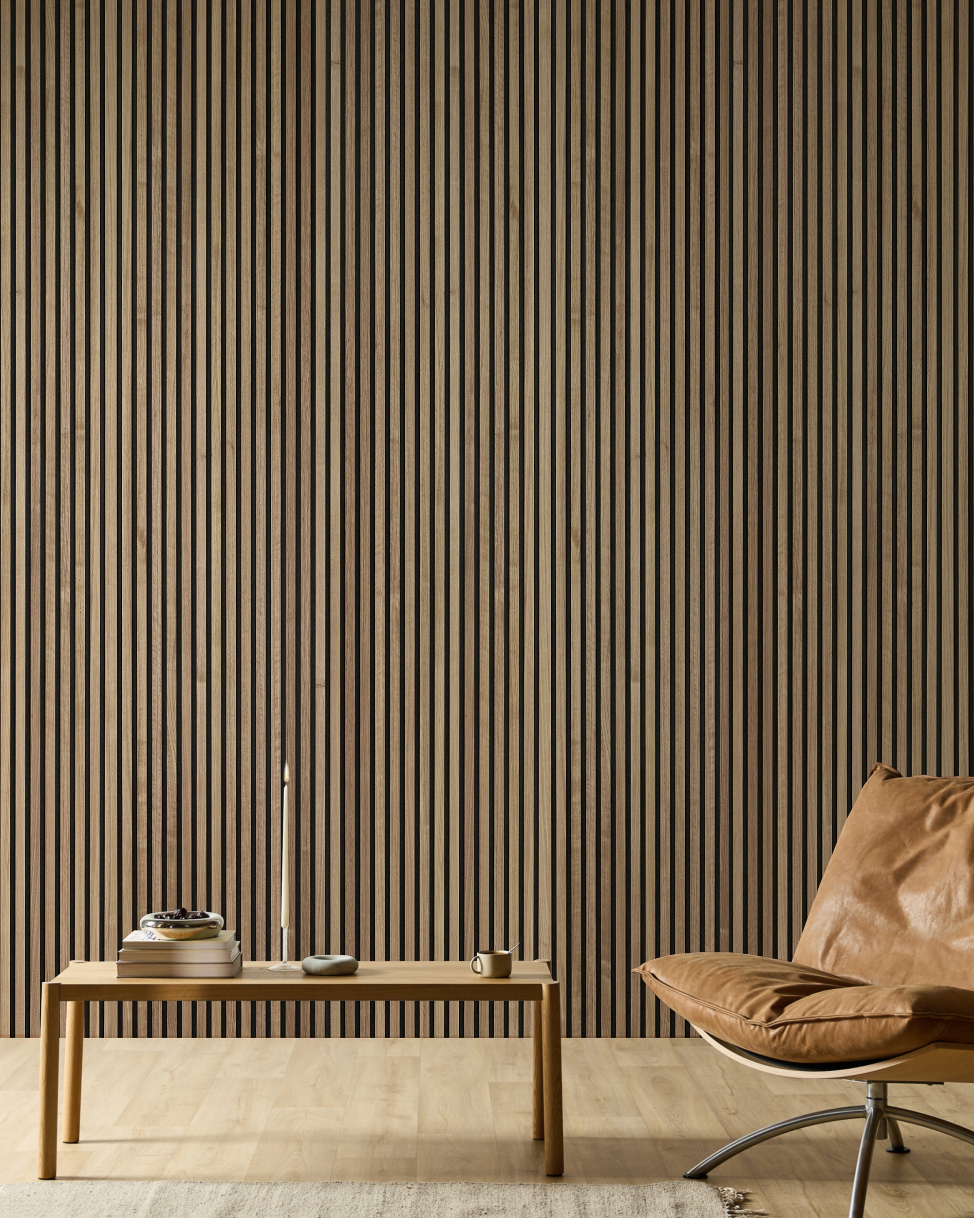 Minimalistischer Raum mit einem Ledersessel, einer Holzbank, Büchern, einer Kerze und einer modernen Akupanel Akustik-Lamellen-Holzwand in neutralen Tönen.