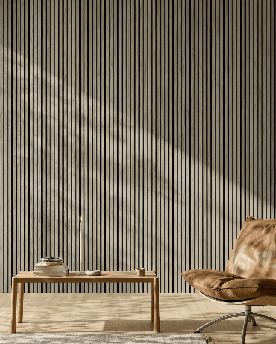 Pièce minimaliste avec un panneau WoodUpp Akupanel 240x60 cm en chêne vieilli avec feutre black, banc en bois, livres, bougie, tasse et fauteuil en cuir fauve.