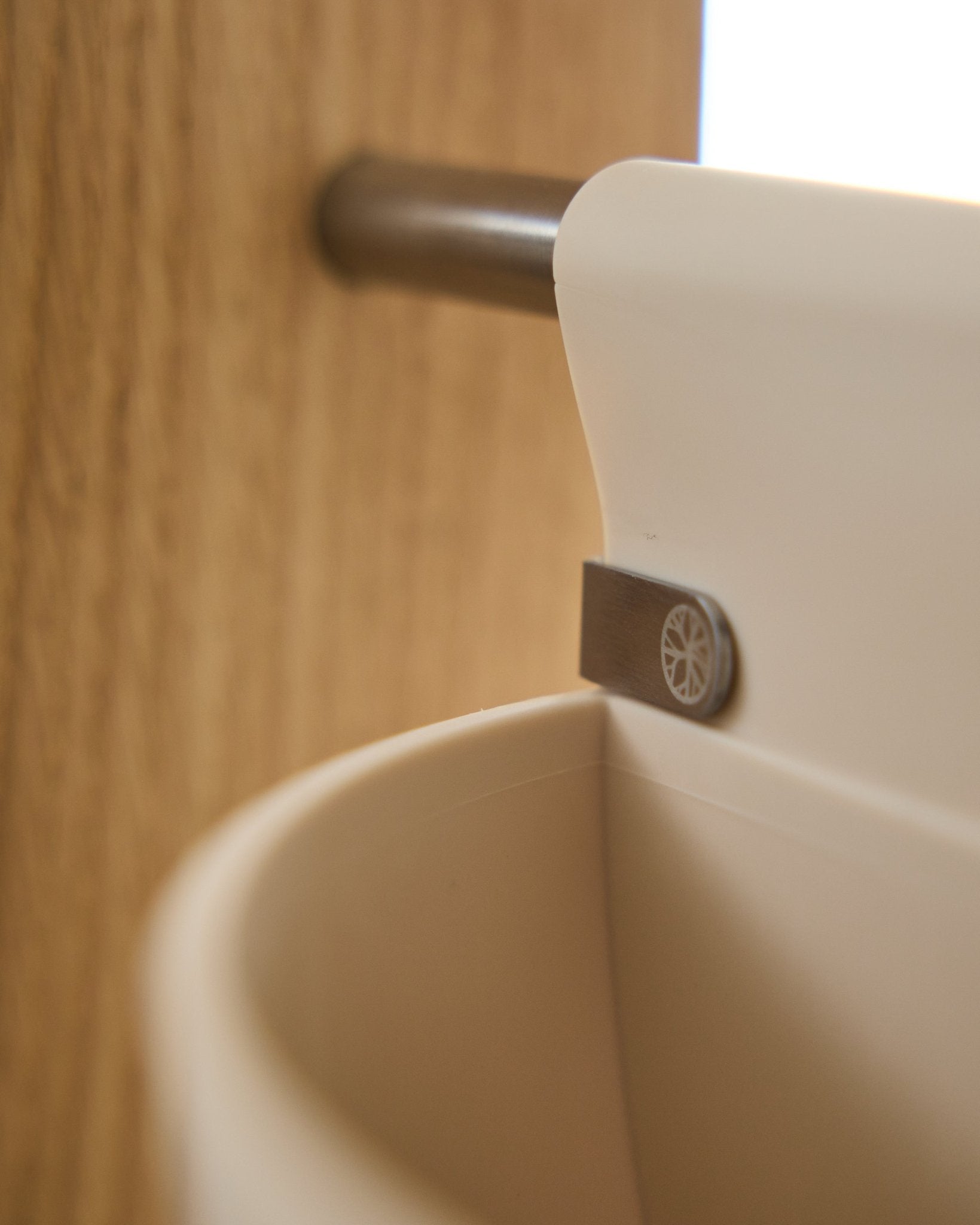 Gros plan sur le Gro | Soft Pocket / BM2 (4 l) en beige clair de WoodUpp, suspendu à une tige métallique fixée au bois ; arrière-plan flou. Accessoire acoustique nordique.