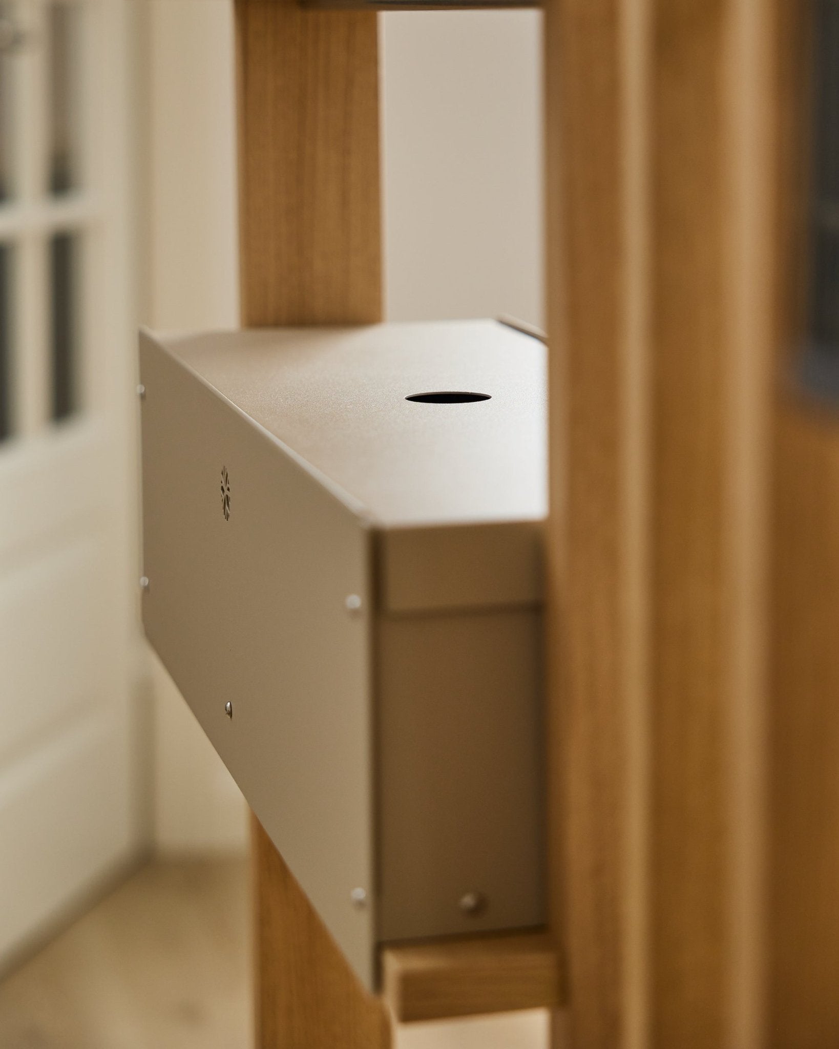 Le Nell | Metal Box / BM2, Beige de WoodUpp est un accessoire en steel thermolaqué de la collection CREATE, placé entre des panneaux acoustiques en bois près d’une porte blanche.