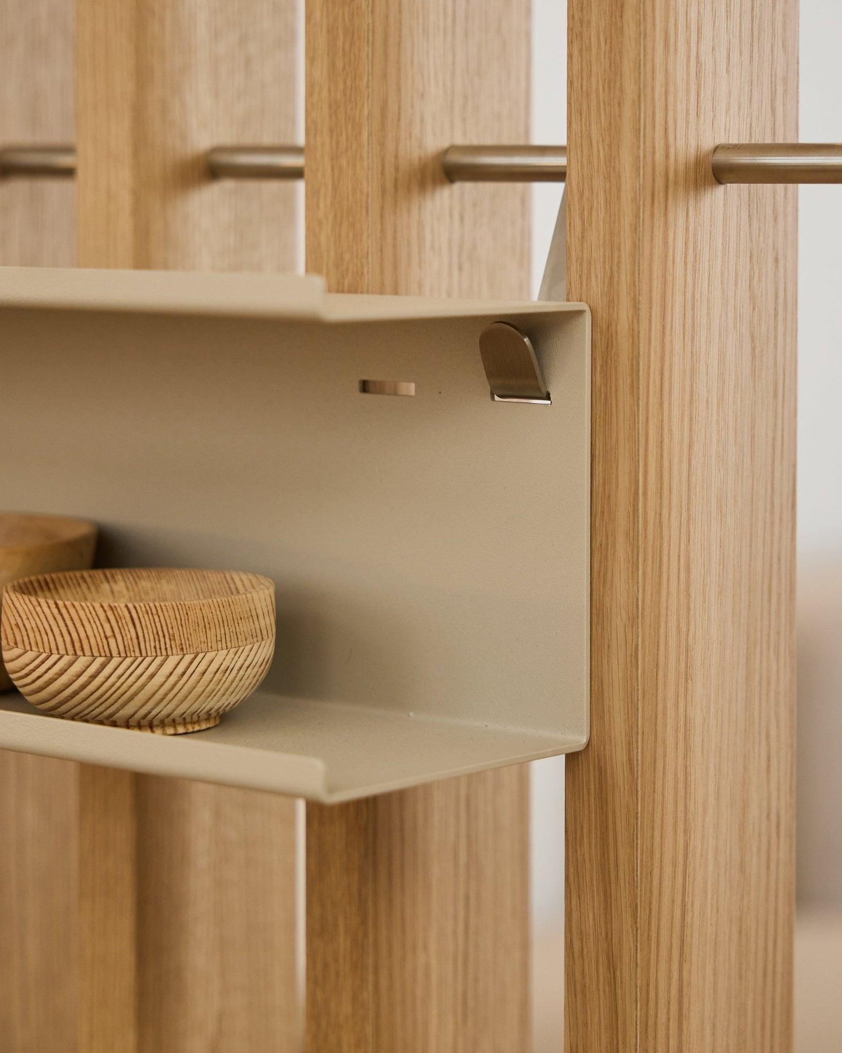 Gros plan sur l’étagère métallique double Nell de WoodUpp / BM1 en beige, 63,5 cm, avec des bols tressés et des lattes acoustiques nordiques en bois verticales fixées sur des tiges en steel.