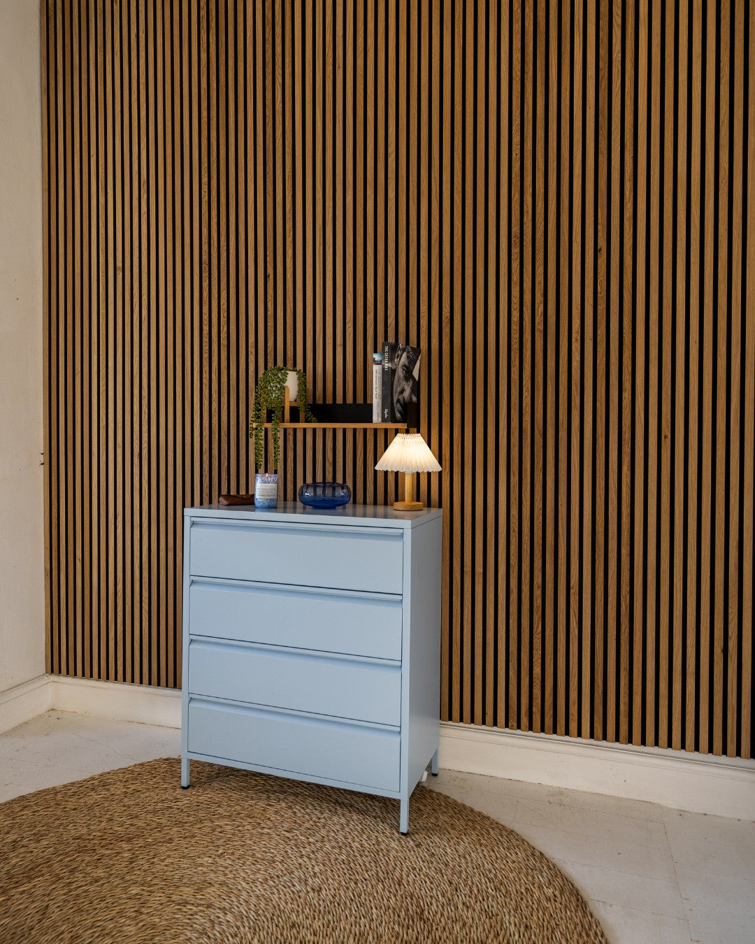Light blue dresser with decorative items against an acoustic panel wall.